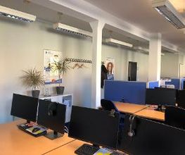 Schulungsraum mit Arbeitsplätzen, bestehend aus 2 Bildschirmen, Tastatur und Headset.