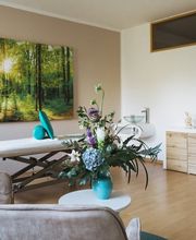 Großzügiger Behandlungsraum von Physiotherapie Birkhoff mit Therapieliege, Sitzbereich, Pflanzen und hellem Ambiente. Das Bild passt zu Manueller Therapie Magdeburg, Massage Magdeburg, Fango Magdeburg und individueller Physiotherapie.