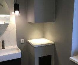 Indirekte Beleuchtung im Bad: Fokus auf Lichtdesign an einem Mauervorsprung in einem modern gestalteten, anthrazitfarbenen Badezimmer.