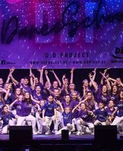 D.D.Project - Hip-Hop Tanzschule Dresden Energiegeladene Tanzgruppe in violetten Outfits bei einer Bühnenperformance, ideal für Hip-Hop, Showdance und Bühnenkunst.