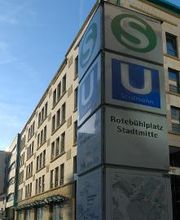 S- iund U-Bahn Hinweisschild Rotebühlplatz Stadtmitte. Dahinter steht ein Bürogebäude.
