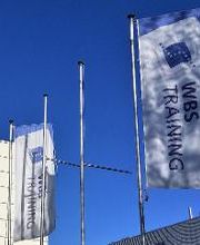 Fahnenständer mit WBS TRAINING Fahnen an einem sonnigen Tag mit blauem Himmel.