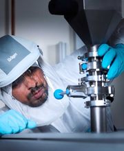 Foto und Filmproduktion Laila Tkotz Forscher im Reinraum prüft industrielle Laboranlage mit Schutzanzug und Handschuhen