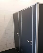 WC-Trennwandanlage in Anthrazit mit Edelstahltürdrückern und Edelstahlfußrosetten.