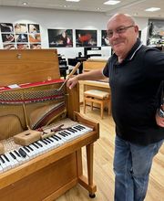 Klavierbauer Jürgen Bode beim Saiten aufziehen an einem Klavier