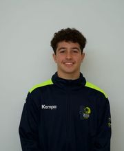 Ein junger Sportler steht vor hellem, neutralem Hintergrund in offizieller Trainingsbekleidung. Das Porträt wirkt ruhig, strukturiert und professionell.
