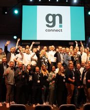 Eine große Gruppe von Menschen steht auf einer Bühne vor einer Leinwand mit dem Logo von „gn connect“. Es handelt sich um eine Veranstaltung, bei der eine Gemeinschaft aus der Gastronomie- und Digitalisierungsbranche zusammenkommt, im Rahmen gastronovi-Events gn connect in Bremen in der alten Werft.