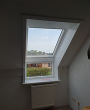 Ein frisch installiertes Dachfenster, das einen klaren Blick auf die Umgebung bietet. Ideal für mehr Licht in kleinen Räumen.