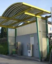 AGROLA Tankstelle in Uznach mit geschwungener Überdachung. Rechts ein Stellschild darüber AGROLA Logo und digitale Preisanzeige. Eine Tanksäule und ein Zahlterminal