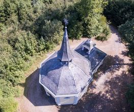 Die historische Heilig Kreuz Kapelle liegt umgeben von Wald.