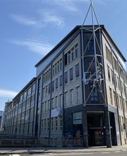 Außenansicht des Gebäudes in Leipzig Süd. Eckgebäude mit einem kunstvollen Gestell auf dem eine Figur angebracht ist.