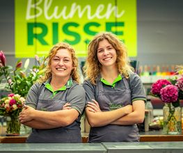 Blumen-Risse Team in der Floristik steht am Tresen vor Logo im Blumenmarkt Lüdinghausen