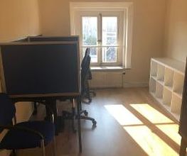 Ein Schulungsraum mit zwei Arbeitsplätzen und einem Regal auf der rechten Seite. Durch ein Fenster gelangen Sonnenstrahlen in den Raum.