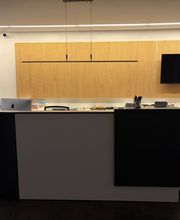 mediaService Bremen | Full-Stack Werbeagentur - Der modern gestaltete Empfangstresen im Eingangsbereich einer Agentur mit einer stilvollen Holzlamellen-Wandverkleidung, Monitor und edler Beleuchtung.