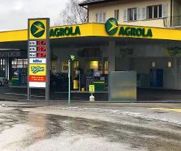 AGROLA Tankstelle in Liebefeld mit TopShop; regnerische Aufnahme; Tankstelle bei Kreisel gelegen; links Totem mit AGROLA Logo, digitaler Preisanzeige, AdBlue und TopShop Logo darunter