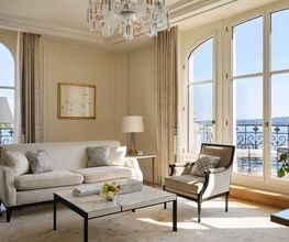 Elegant living room with neutral tones, large windows, and lake views at The Woodward Geneva suite.