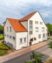 Dreistöckiges Bürogebäude mit Spitzdach an einer Straße.