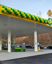 AGROLA Tankstelle in Illnau; an Dach Luftballone in gelb und grün angebracht; mehrere Tanksäulen; im HIntergrund TopShop; rechts Bäume