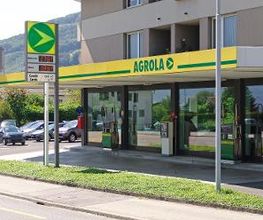 AGROLA Tankstelle in Grabs bei Mitsubishi Autogarage; Tankstelle vor Fensterfront; zwei Tanksäulen und ein Zahlterminal; AGROLA Logo mit digitaler Preisanzeige; links Mitsubishi Logo