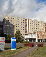 Bürogebäude mit Straße davor. Auf dem Rasen sind zwei Firmenschilder zu sehen.