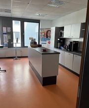 Moderne Küche mit Kaffeemaschine und Mikrowelle sowie einer Theke und Stehtischen. Pausenraum.