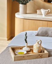 Massage bed at Aelia Spa with a wooden tray holding a small ceramic pitcher, bowl, and olive branch, set in a softly lit wellness suite.