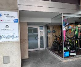 Eingang mit Beschilderung WBS TRAINING, Eingangstür, rechts Fahrradladen.