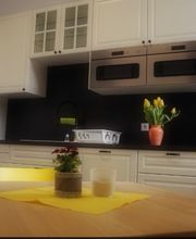 Küche mit Kühlschrank, zwei Mikrowellen und Tisch und Stühlen.