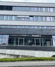 Außenansicht des Gebäudes. Dunkelgrauer Klinker und viele Fenster.