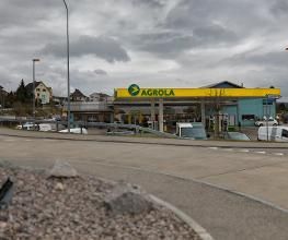AGROLA Tankstelle in Winznau; im Vordergrund Strasse - Tankstelle mit TopShop; links Totem mit AGROLA Logo und digitaler Preisanzeige