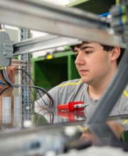 Elektriker Lehrling bei der Arbeit an einem Schaltkasten.