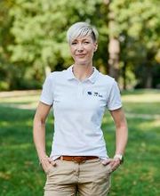 Eine Frau mit kurzen, blonden Haaren in beiger Hose und weißem Poloshirt.
