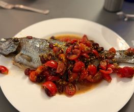 Geschlossene Gesellschaft Ganzer Fisch mit Tomaten und Kräutern, kreativ zubereitet und präsentiert bei Geschlossene Gesellschaft Hamburg.