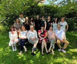 Eine Gruppe von mehreren Frauen und Männern posiert für ein Foto in einem Garten.