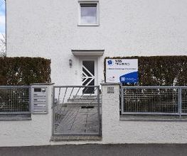 Eingangstor zum weißen Haus mit Hecke und WBS TRAINING Schild.