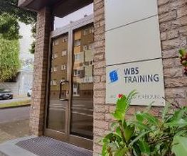Äußere Eingangstür mit Firmenschild auf dem „WBS TRAINING“ steht.