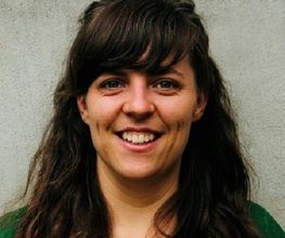 Portrait einer Bildungsreferentin mit schwarzen langen Haaren. Die Dame lächelt freundlich in die Kamera.