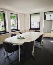 Konferenzraum mit großem Tisch und 6 Stühlen sowie einem Flipchart
