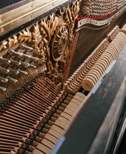 Detailaufnahme der Klaviermechanik mit Saiten, Hämmern und kunstvoller Verzierung. Veranschaulicht die präzise Handwerkskunst im Klavierbau.