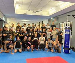 Gemeinschaftliches Kampfsporttraining in moderner Sportschule mit motivierten Teilnehmerinnen und Teilnehmern aller Altersgruppen.