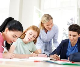 Nachhilfelehrerin unterstützt ihre Schüler beim Lernen am Tisch.