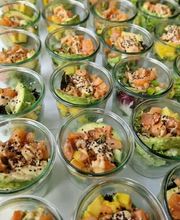 dean&david Catering | Pforzheim - Nahaufnahme von Lachs Bowls im Glas mit Avocado, Mango, Salat, Sesam und cremigem Dressing als frische Bowl-Auswahl für Events.