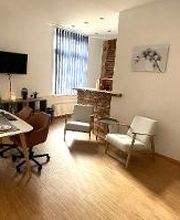 Beratungsraum mit Parkettfußboden, hellen Holzmöbeln, Cognacfarbenen Clubsesseln und Kindermalecke