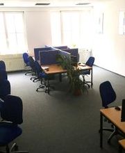 hier sind 9 Arbeitsplätze im Großraumbüro abgebildet mit je zwei Bildschirmen, Headset, Tastatur und Maus