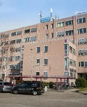 Das Bild zeigt das Gebäude der Neureutherstraße von außen. Hellbraune Fassade und viele Fenster.