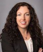 Portrait einer Bildungsreferentin, mit schwarzen, langen gelockten Haaren, die freundlich in die Kamera lächelt.