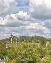Blick auf die Gärten der Welt. Meer aus grünen Bäumen, im Hintergrund eine Seilbahn.