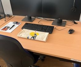 Arbeitsplatz bestehend aus 2 PC-Bildschirmen, Tastatur, Maus und Headset sowie einem Bürostuhl.