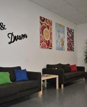 Pausenraum mit 3 Sofas und bunten Kissen. An der Wand mehrere farbenfrohe Bilder und ein Wandtattoo "Relax & Dream"