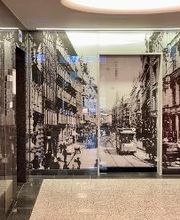 Flurbereich mit einem schwarz-weißem Wandgemälde auf dem eine Straße mit Cable Car und Kutsche zu sehen ist. Links befinden sich Fahrstühle.